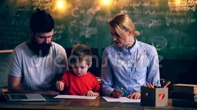 父母教一个男孩在学校教室画画。 教师教一个男孩借鉴绿色学校董事会的背景